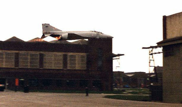 Un Phantom II de la RAF en passage bas, post combustion allumée, entre 2 hangars de la base de St Athan (Galles)