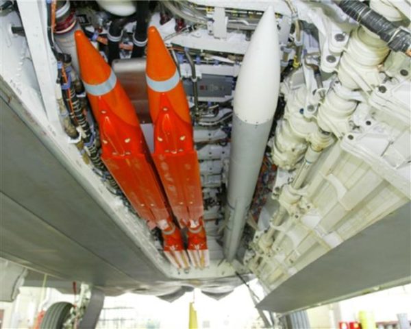 Un AIM-120, en gris, accompagné par quatre GBU-39 orange, dans la soute d'un F-22 raptor