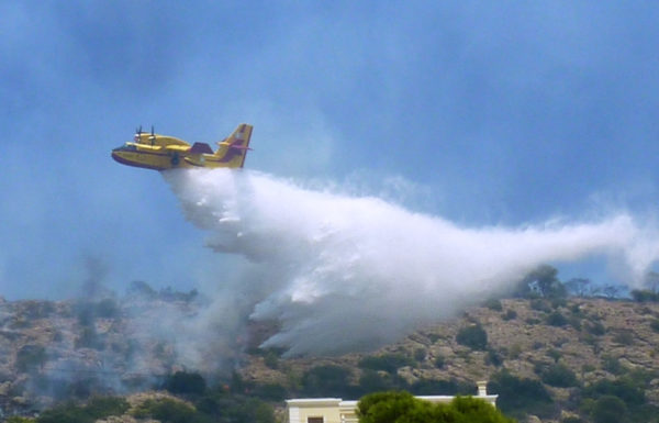 Bombardier CL-415 grec larguant sa charge d'eau sur une cible péri-urbaine.