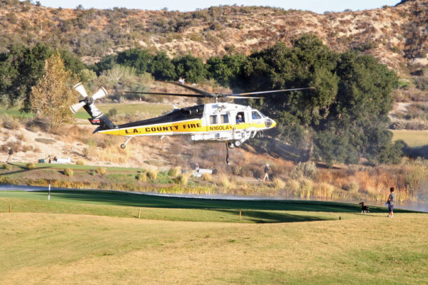 Un Sikorsky S-70 des pompiers du comté de Los Angeles avitaille en eau au-dessus d'un terrain de golf.